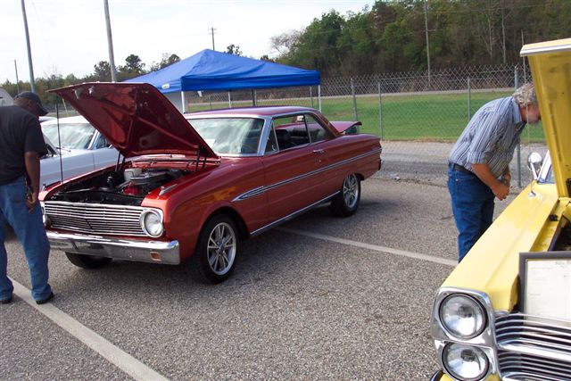 Red coupe with hood open, chrome trim, custom wheels, parked outdoors