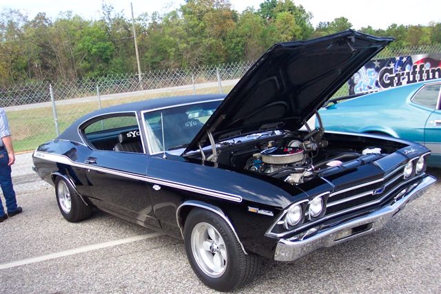 Black 1969 Chevrolet Chevelle SS with hood open, parked next to a teal car