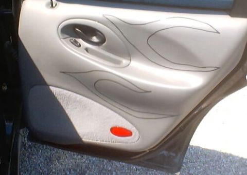 1999 Ford Taurus - Close-up of a car's interior door panel custom flame graphics and a red reflector light.