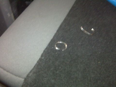 2008 Jeep Wrangler - Close-up of two small metal clips resting on a textured fabric surface.