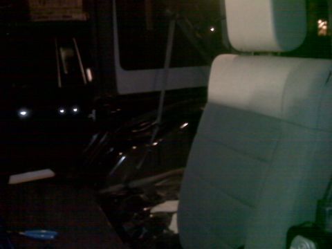2008 Jeep Wrangler - The interior of a vehicle shows light-colored seat covers and a dark dashboard with a blue tool on the floor.