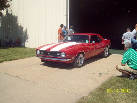 1995 Ford Probe - A red 1967 Chevrolet Camaro SS coupe with white racing stripes is parked outside a building.