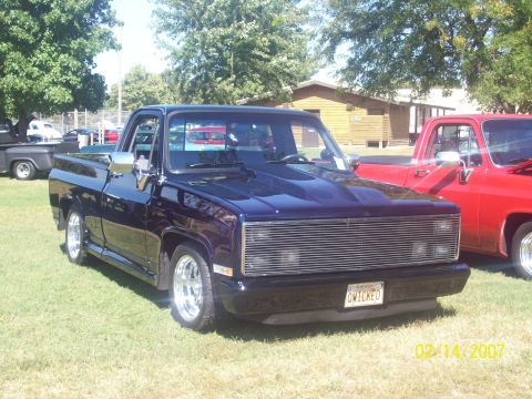 1995 Ford Probe - A dark blue pickup truck with a custom hood and grille is parked on a grassy field next to a red truck.