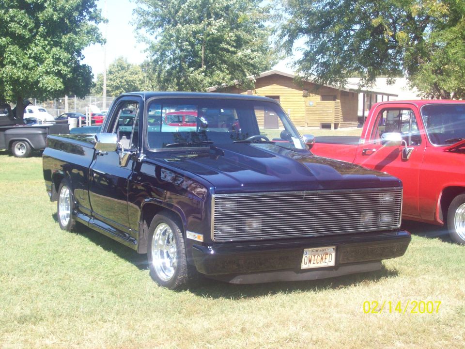 Deep purple lowered square-body Chevy C10 pickup on grass at a car show