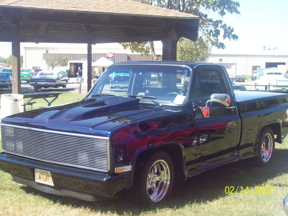 Purple-blue candy square-body Chevy C10 pickup with billet grille at a car show