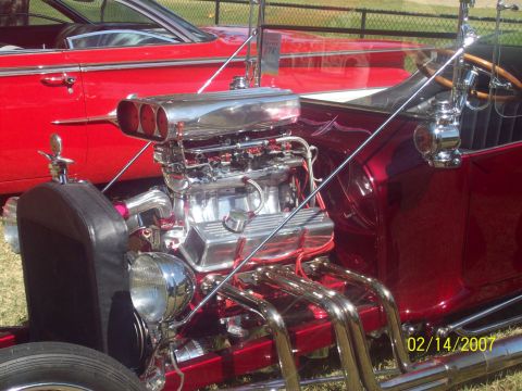 1995 Ford Probe - A custom hot rod with a prominent chrome engine and headers is displayed next to a red vehicle.