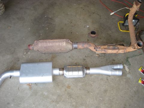 1995 Ford Bronco - Comparison of old and new exhaust system components laid out on a concrete floor.