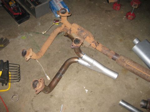 1995 Ford Bronco - Assembly of exhaust system parts, including a Y-pipe and catalytic converter, laid out on a concrete floor.