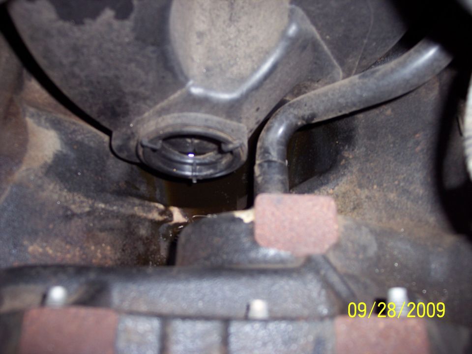 Engine component with a fluid leak, showing a black hose and a dark liquid dripping