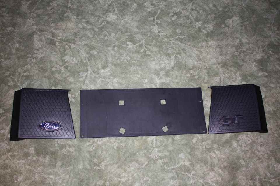 Black Ford GT emblems and license plate bracket on a textured surface