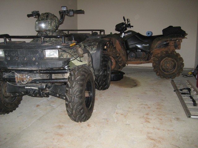 Front view of a camouflage ATV with a black ATV behind it in a garage