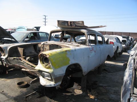 1986 Ford Bronco - This car appears to be a classic sedan in a state of disrepair at a junkyard.