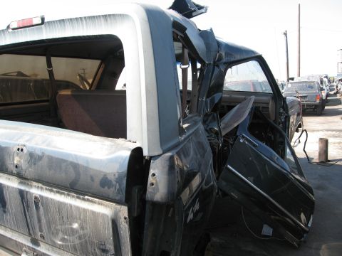1986 Ford Bronco - This heavily damaged SUV, possibly a 1986 Ford Bronco, is seen from the 3/4 front angle, revealing its interior and rear sections.