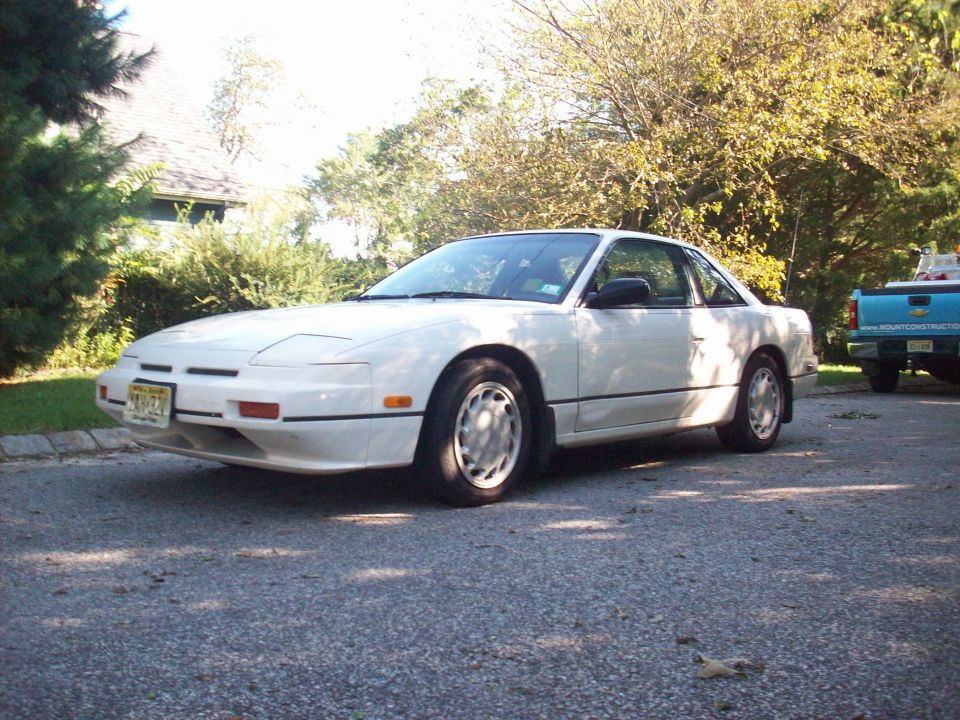 White coupe with pop-up headlights parked on asphalt, front-left view