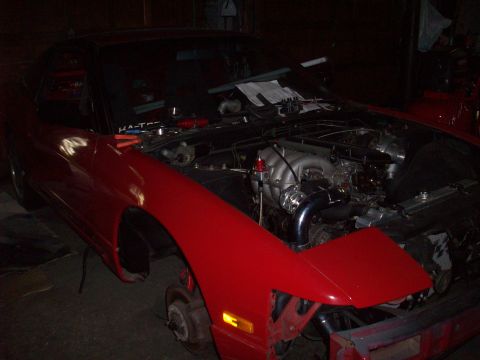 1992 Nissan 240SX - A red car, likely a Nissan 240SX from the late 80s or early 90s, is shown with its hood open and engine exposed.