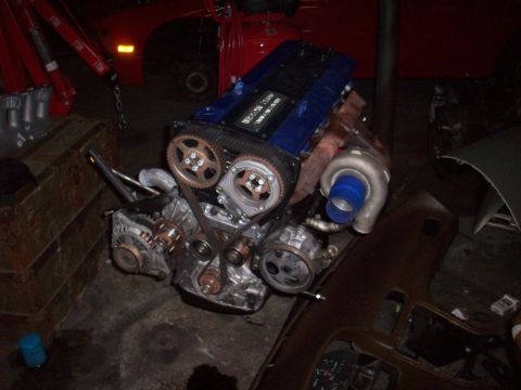 1992 Nissan 240SX - A Nissan SR20DET engine, identifiable by its blue valve cover and turbocharger, is shown disassembled.