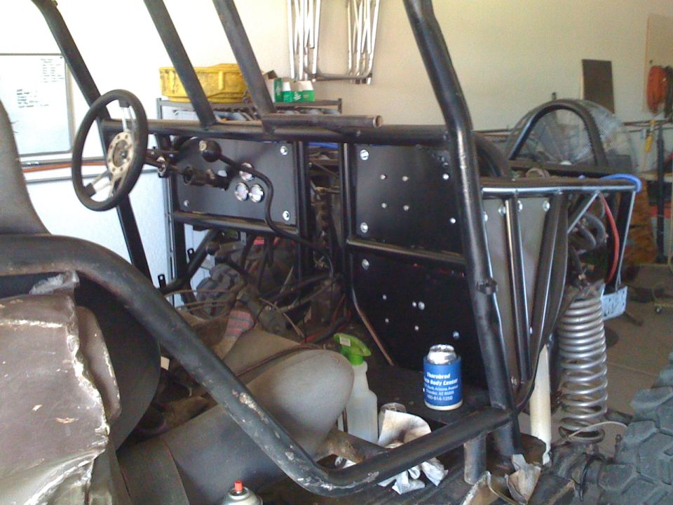 Custom buggy interior with roll cage, steering wheel, and dashboard. A can of spray paint sits on the floor