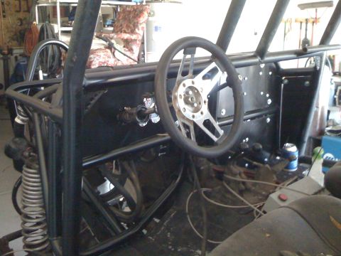1966 Ford Bronco - Interior view of a custom-built off-road vehicle, a roll cage and a racing-style steering wheel.