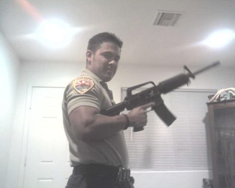 1982 Ford Bronco - A man in a sheriff's uniform poses with a rifle inside a room.