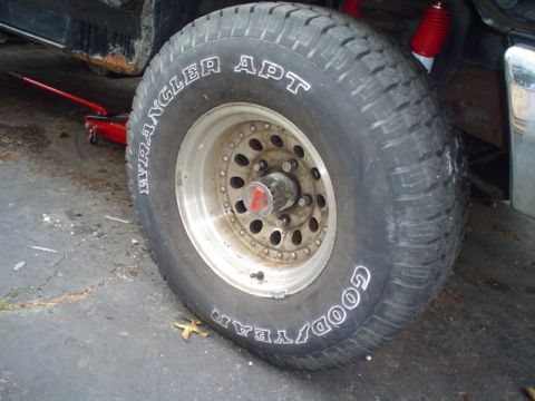 1988 Ford Bronco - A close-up view of a tire and wheel assembly, with a red jack visible beneath the vehicle.