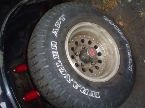 1988 Ford Bronco - Spare tire and red suspension parts are visible inside a vehicle's storage area.