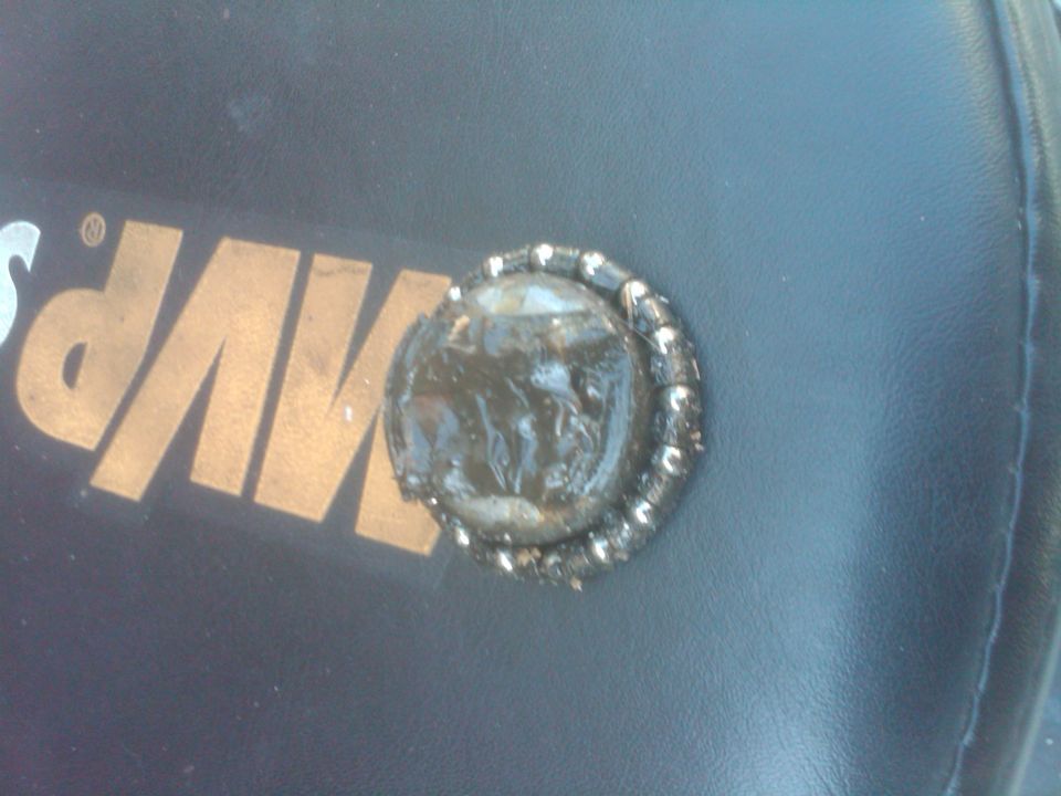 Close-up of a dark interior surface with a circular emblem that has a metallic border and a dark, possibly damaged, center