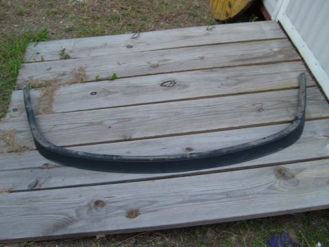 1992 Ford Bronco - A black trim piece, likely a fender flare or bumper trim, rests on weathered wooden planks.