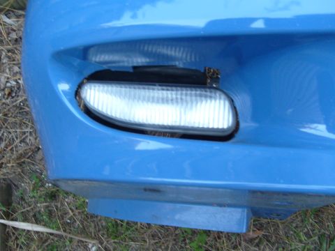 1992 Ford Bronco - Close-up of a blue car's front bumper, showing a fog light assembly.