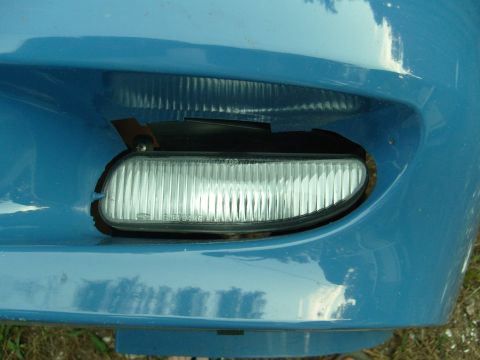 1992 Ford Bronco - Close-up of a blue vehicle's front bumper reveals a fog light assembly and a watermark.