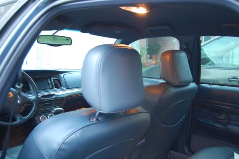 1985 Mercury Grand Marquis - Interior view of a car with gray seat covers, showing the dashboard and steering wheel, with another vehicle visible outside.