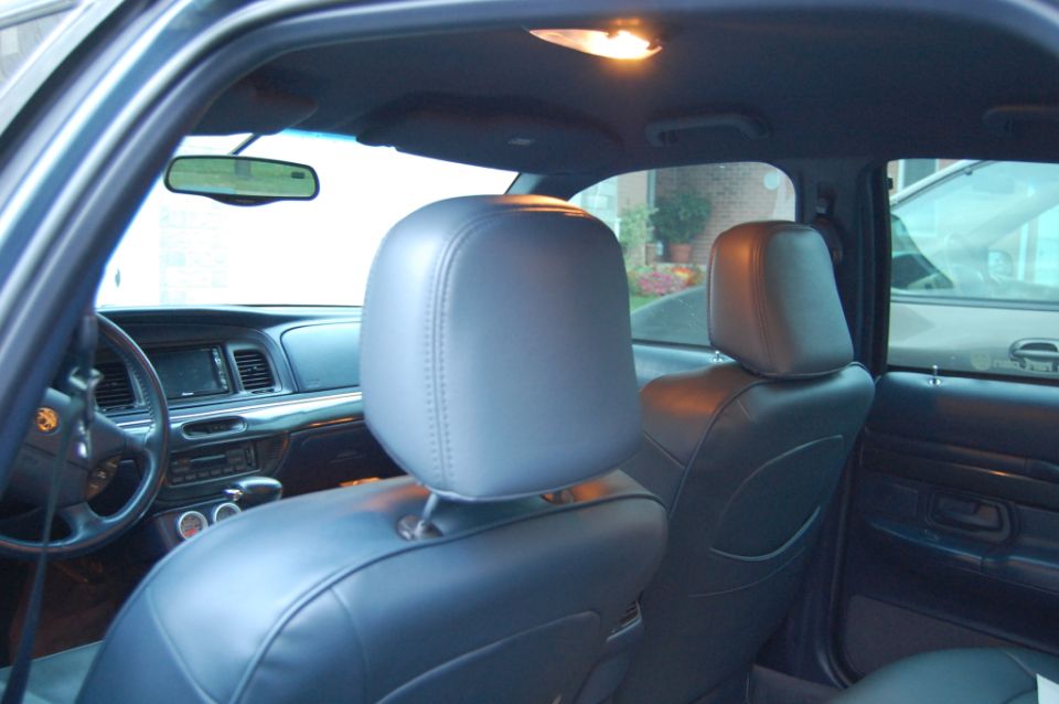 Car interior with gray leather seat covers, dashboard, and steering wheel. Another car is visible through the window
