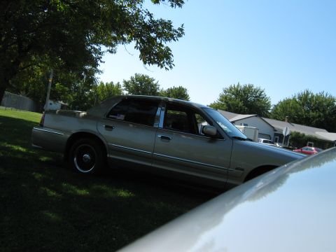 2000 Mercury Grand Marquis - A tan sedan is parked on a grassy lawn under a clear blue sky.