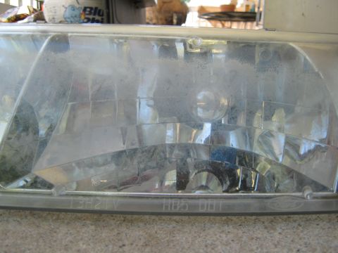 2000 Mercury Grand Marquis - Headlight assembly part shown in detail, with some text visible on the lens.