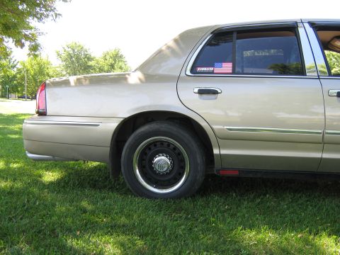 2000 Mercury Grand Marquis - A tan sedan is parked on a grassy lawn with trees in the background.