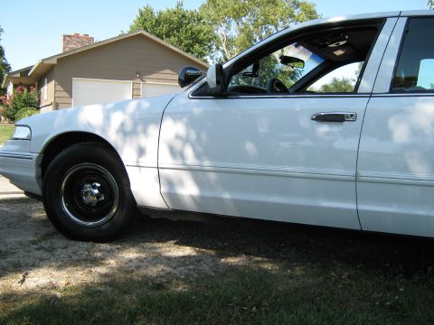 2000 Mercury Grand Marquis - Side profile of a white 2000 Mercury Grand Marquis parked outdoors on a sunny day.