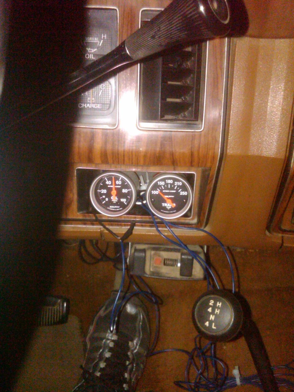 Dashboard with oil and temperature gauges, plus a 4x4 shifter. Wires are visible