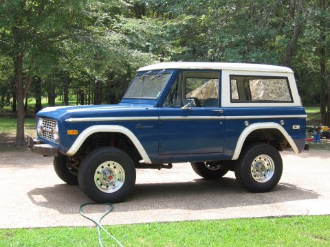1967 Ford Mustang - This blue Ford Bronco features a white hardtop and is parked outdoors on a gravel surface.