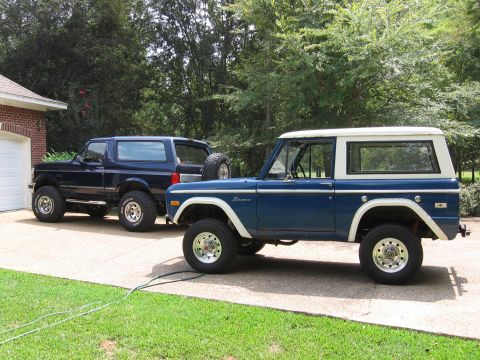 1967 Ford Mustang - Two generations of Ford Broncos are parked side-by-side in a driveway.