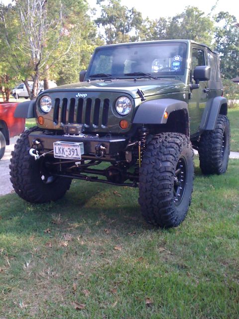 1991 Ford Bronco - This modified Jeep Wrangler sits on a grassy lawn, its lifted suspension and aggressive tires.