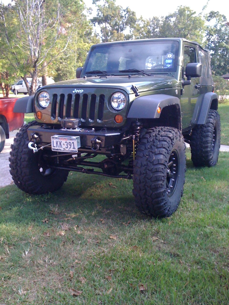 Green Jeep Wrangler with large off-road tires and a winch on the front bumper