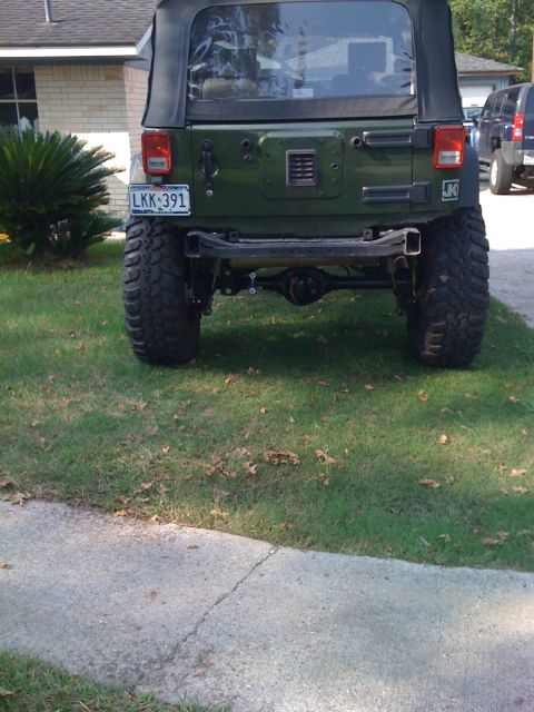 1991 Ford Bronco - Rear view of a green Jeep Wrangler with oversized tires and a soft top.