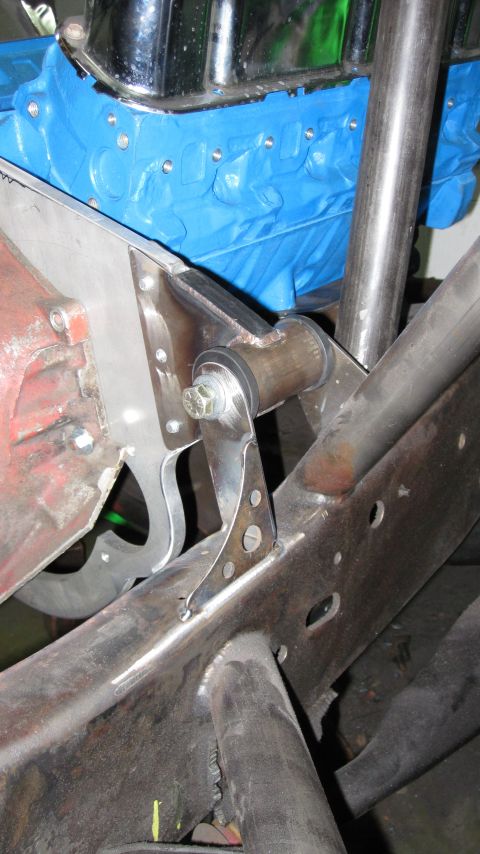 1995 Ford Bronco - Close-up view of a custom-fabricated suspension bracket mounted to a vehicle's frame, adjacent to a blue engine block.