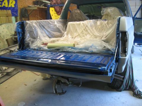 1992 Ford Bronco - Rear view of a blue pickup truck bed with the tailgate down and the interior covered in plastic sheeting.