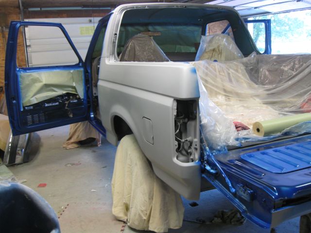 1992 Ford Bronco with doors open, covered in plastic and primer for bodywork