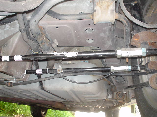 Adjustable threaded chassis brace bars with turnbuckle sleeves installed under a car