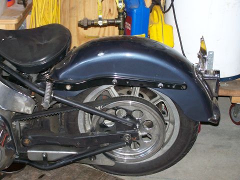 1988 Suzuki Samurai - Close-up view of a motorcycle's rear wheel, fender, and seat in a garage setting.