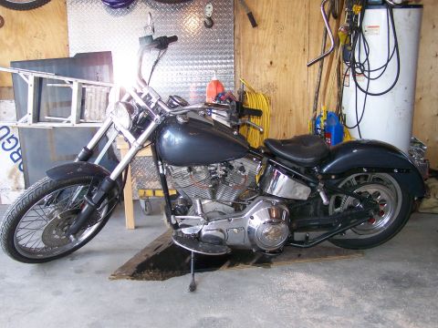 1988 Suzuki Samurai - A dark blue motorcycle is parked inside a garage, resting on a wooden ramp.