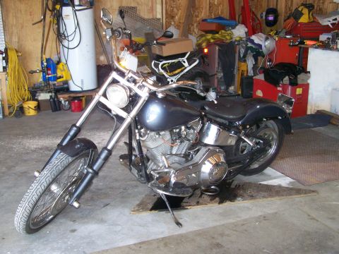 1988 Suzuki Samurai - A motorcycle sits in a cluttered garage, with tools and equipment visible in the background.