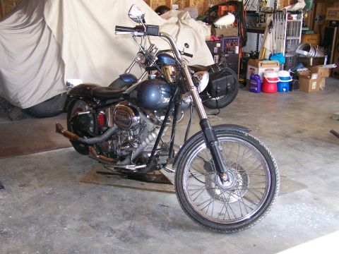 1988 Suzuki Samurai - A blue motorcycle is parked in a garage, with another vehicle covered in a tarp behind it.