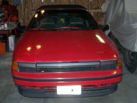 1988 Suzuki Samurai - This red convertible sports car has a black grille and bumper trim. The license plate area is blank.